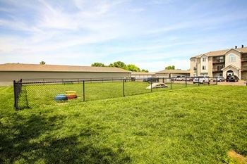 a fenced in yard with a dog park and apartment buildings